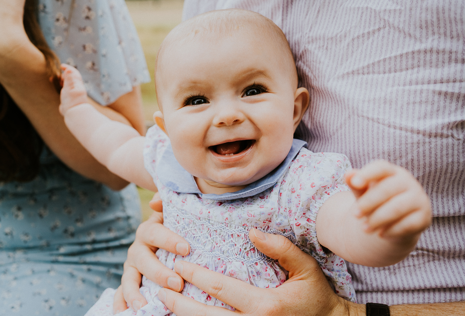 SPRING MINI PHOTO SESSIONS CLOSE UP BABY GIRL SMILING SITTING ON PARENTS LAP