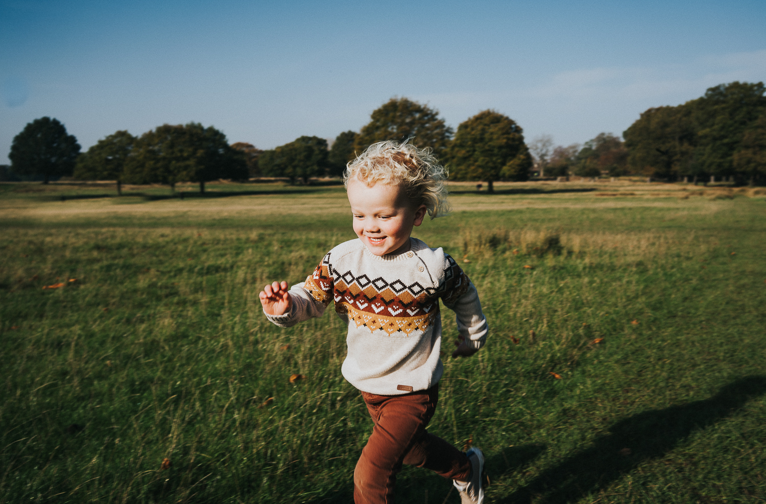 SPRING MINI PHOTO SESSIONS LITTLE BOY WITH BLONDE CURLS RUNNING AND SMILING IN RICHMOND PARK LONDON