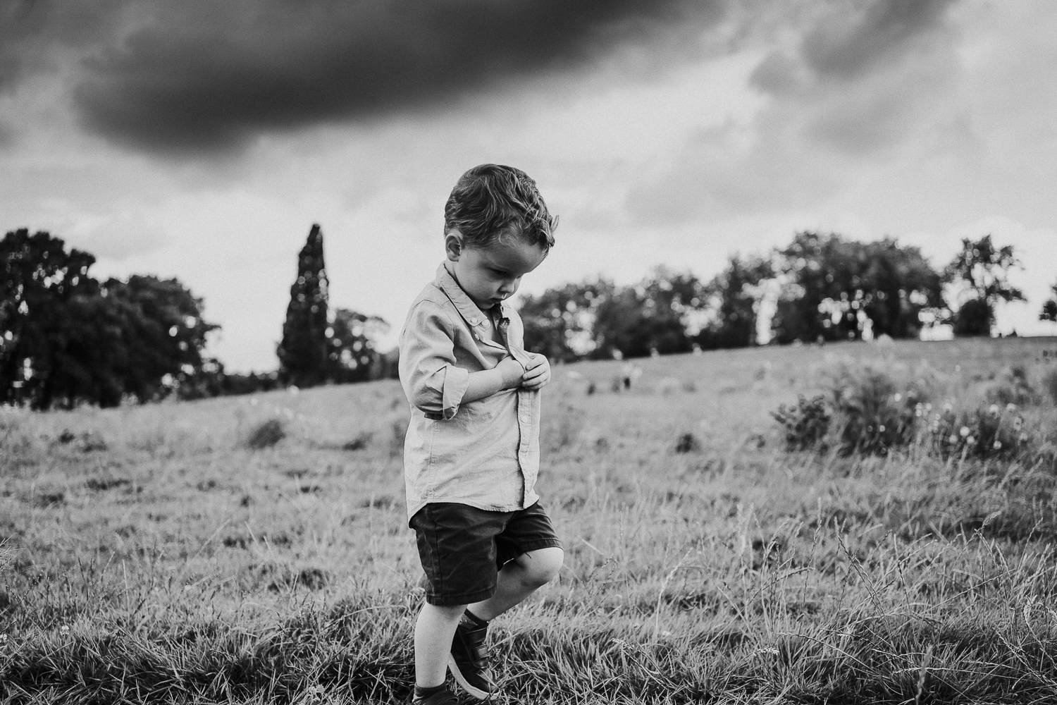 SPRING MINI PHOTO SESSIONS BOY WALKING IN GLADSTONE PARK WITH STORMY SKY BLACK AND WHITE