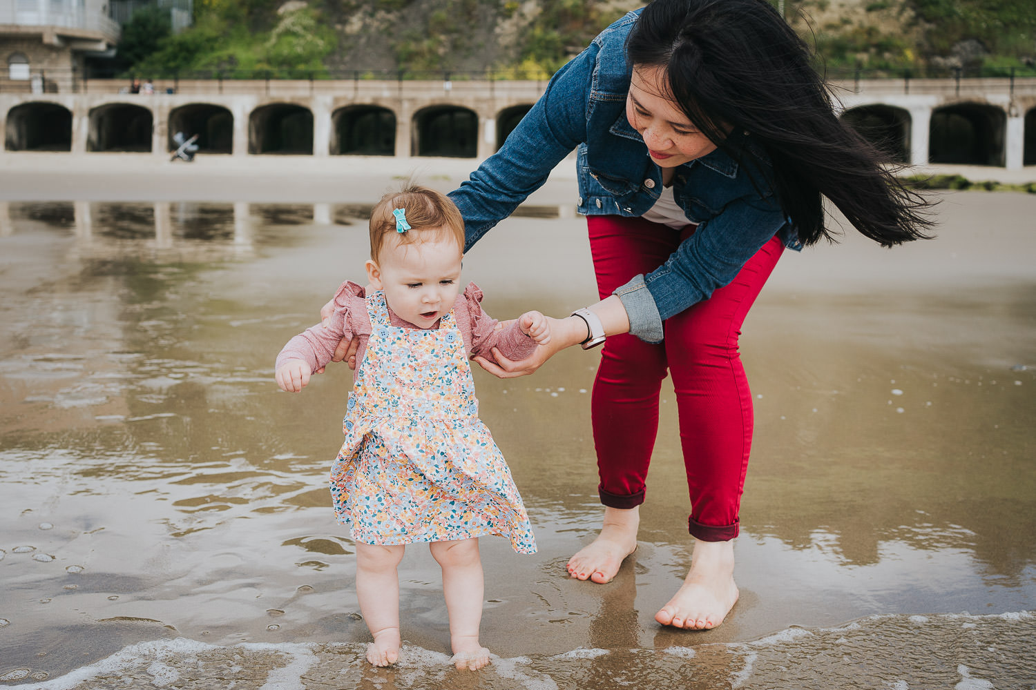 folkestone family photo shoot on the beach black and white photo toddler girl paddling with parents