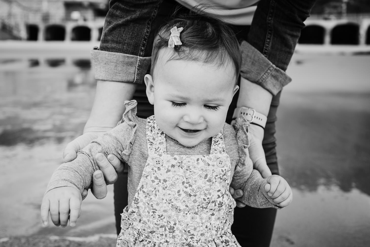 folkestone family photo shoot on the beach black and white photo toddler girl paddling with parents
