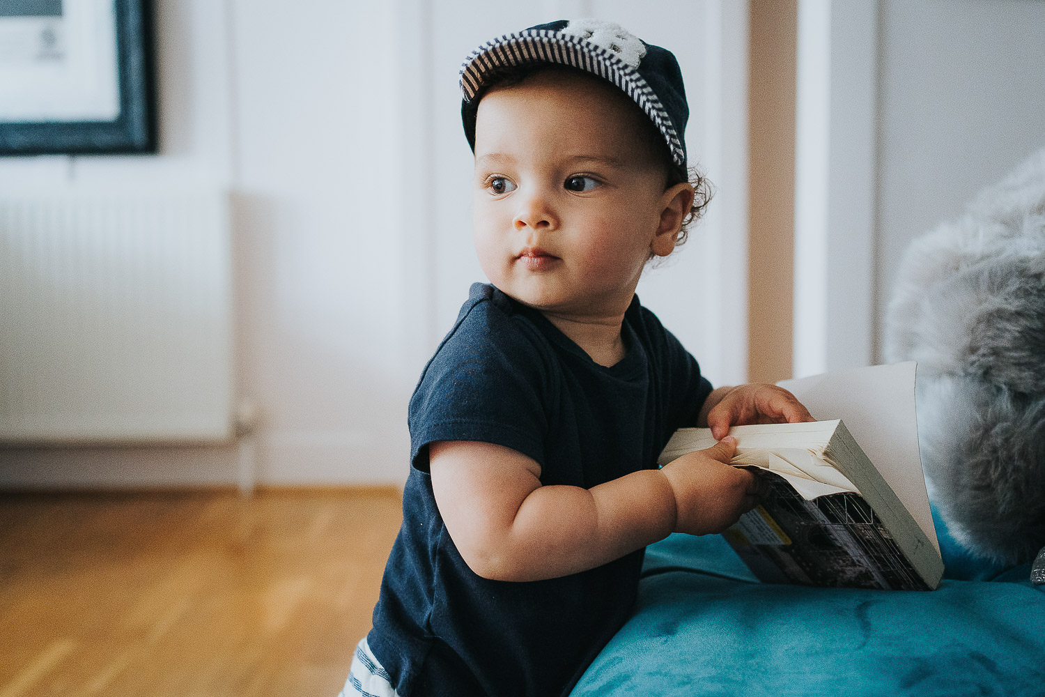 family photo shoot at home toddler boy with cap on holding an open book