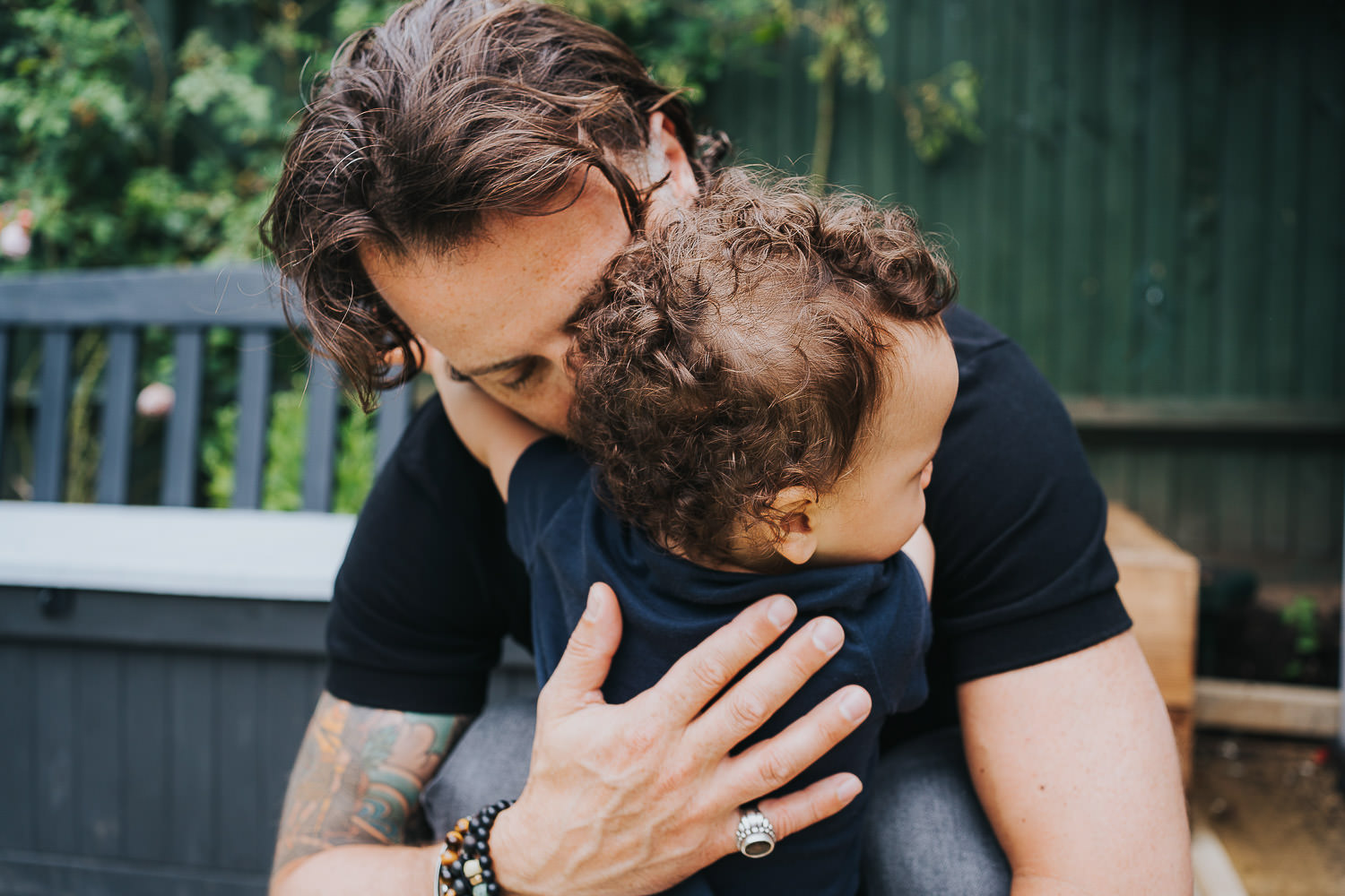 family photo shoot at home toddler boy hugging his dad in the garden