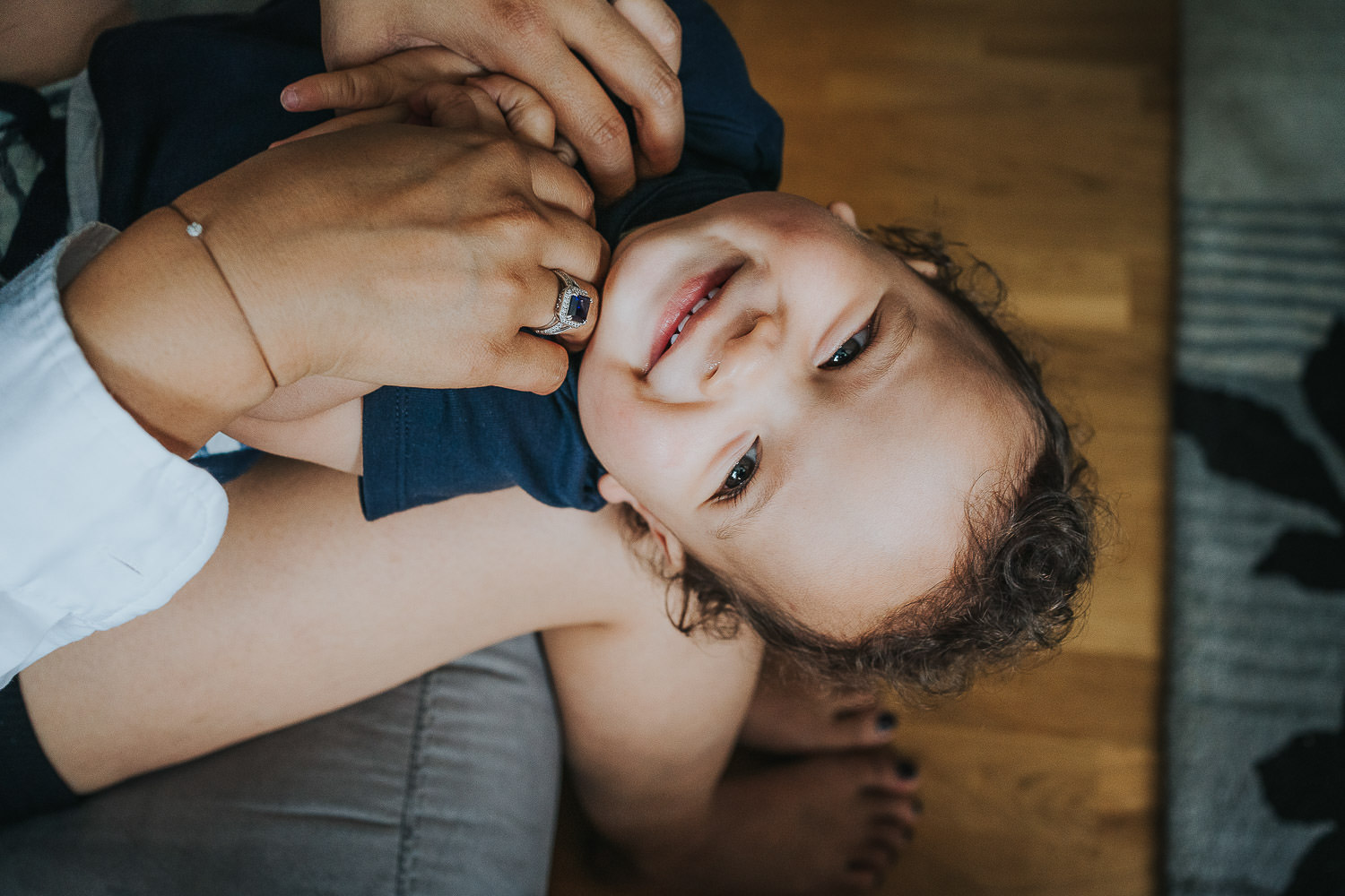 family photo shoot at home toddler boy laughing on mums lap close up