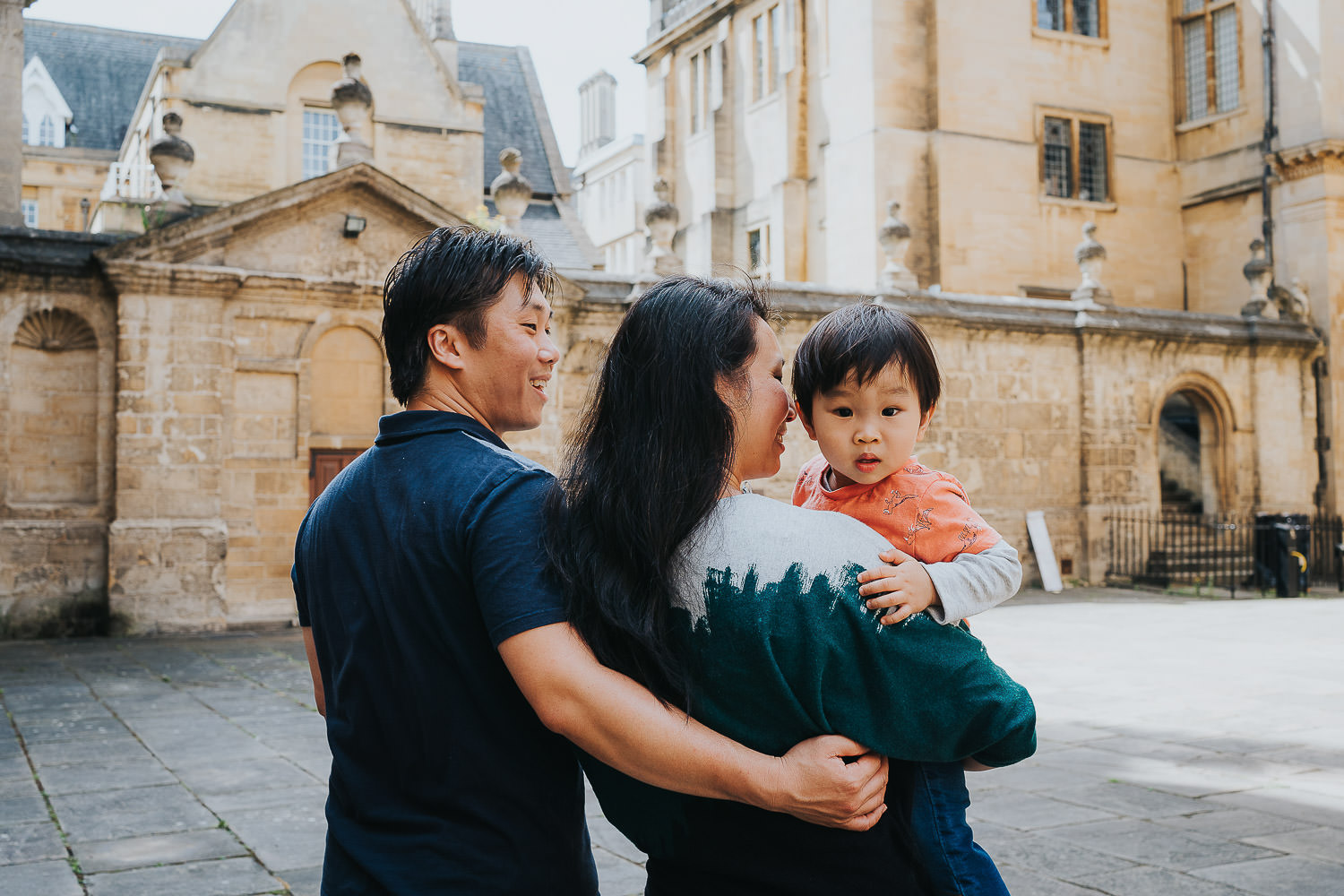 oxford family photo shoot parents walking and holding toddler who is looking back at camera