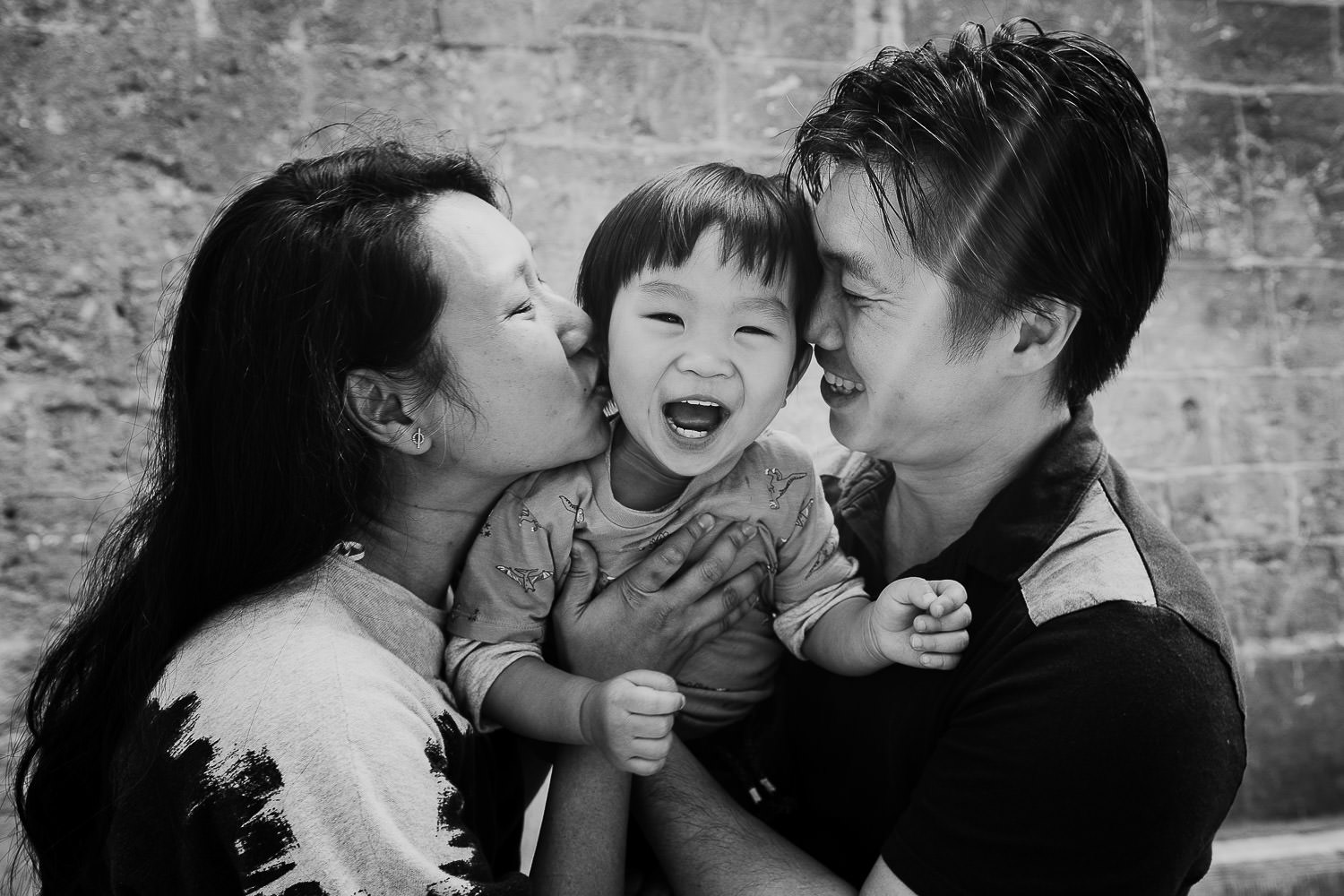 oxford family photo shoot black and white shot of toddler and parents in tight embrace laughing