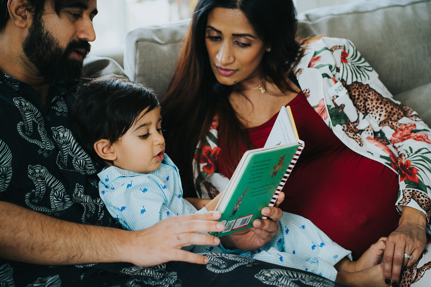 SHOREDITCH MATERNITY PHOTO SHOOT TODDLER BEING READ TO BY PARENTS ON SOFA