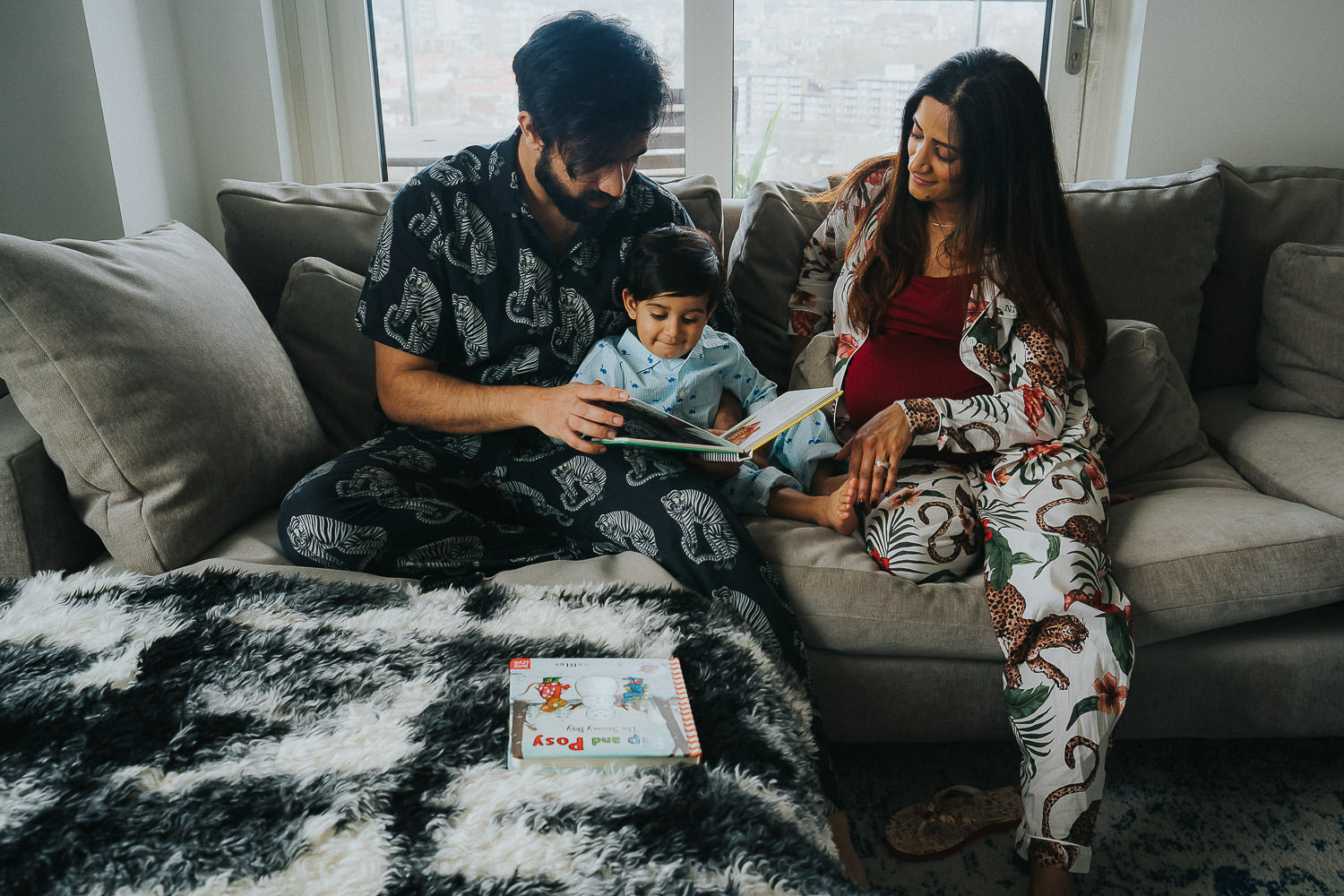 SHOREDITCH MATERNITY PHOTO SHOOT TODDLER BEING READ TO BY PARENTS ON SOFA
