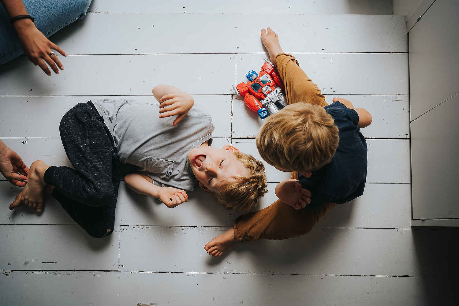 two young boys rough play on floor