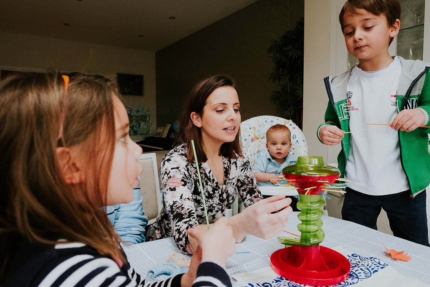 at home family photo shoots in london family playing kerplunk game at table