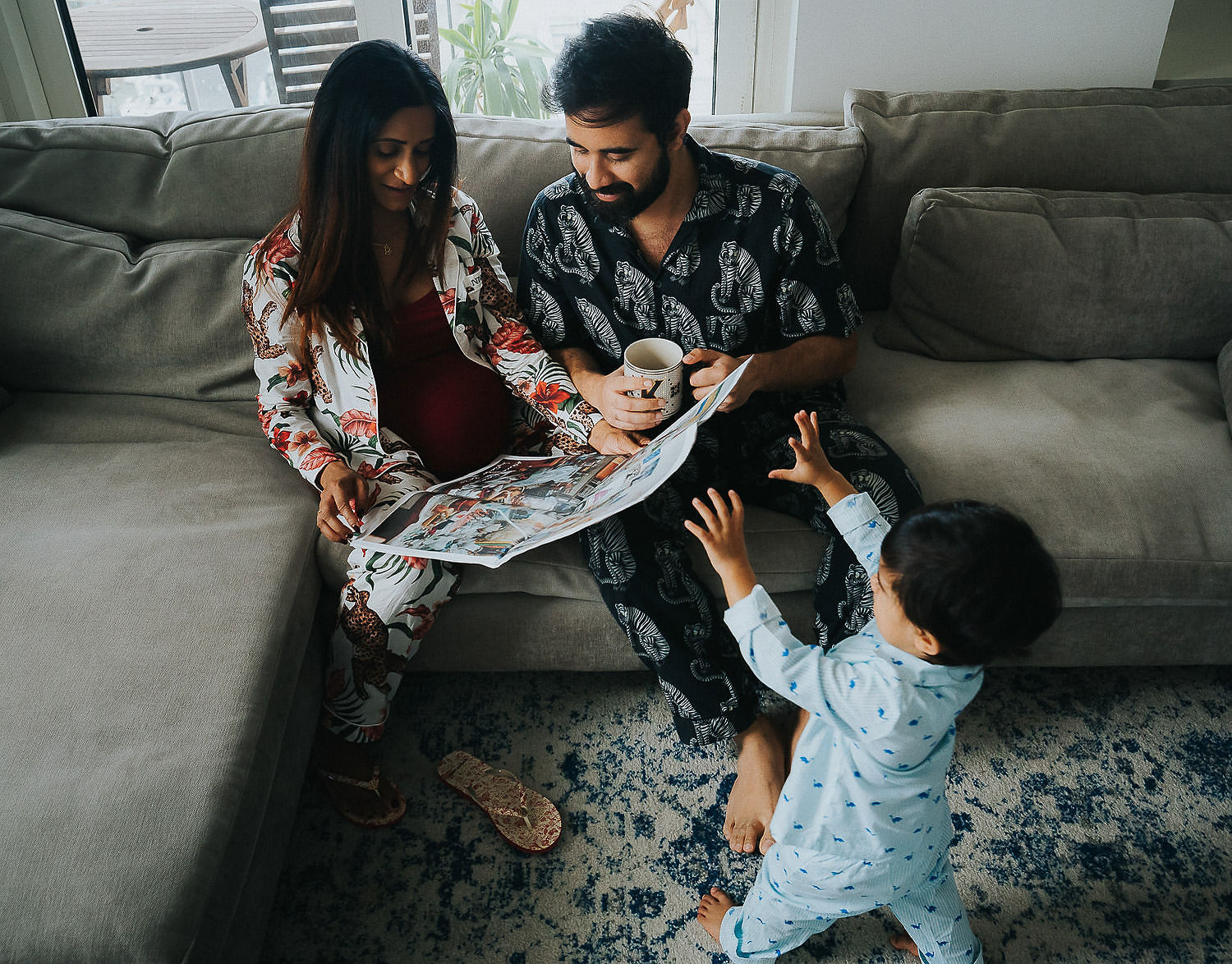 at home family photo shoots in london parents reading newspaper with young boy in pyjamas