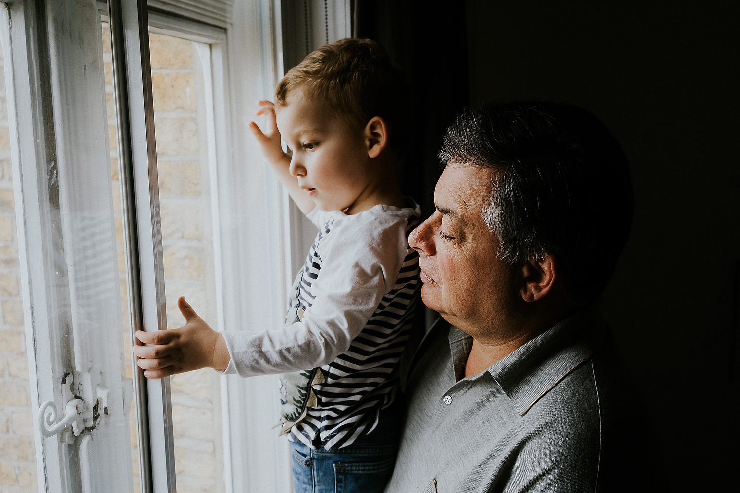 at home family photo shoots in london grandfather and boy looking out of the window