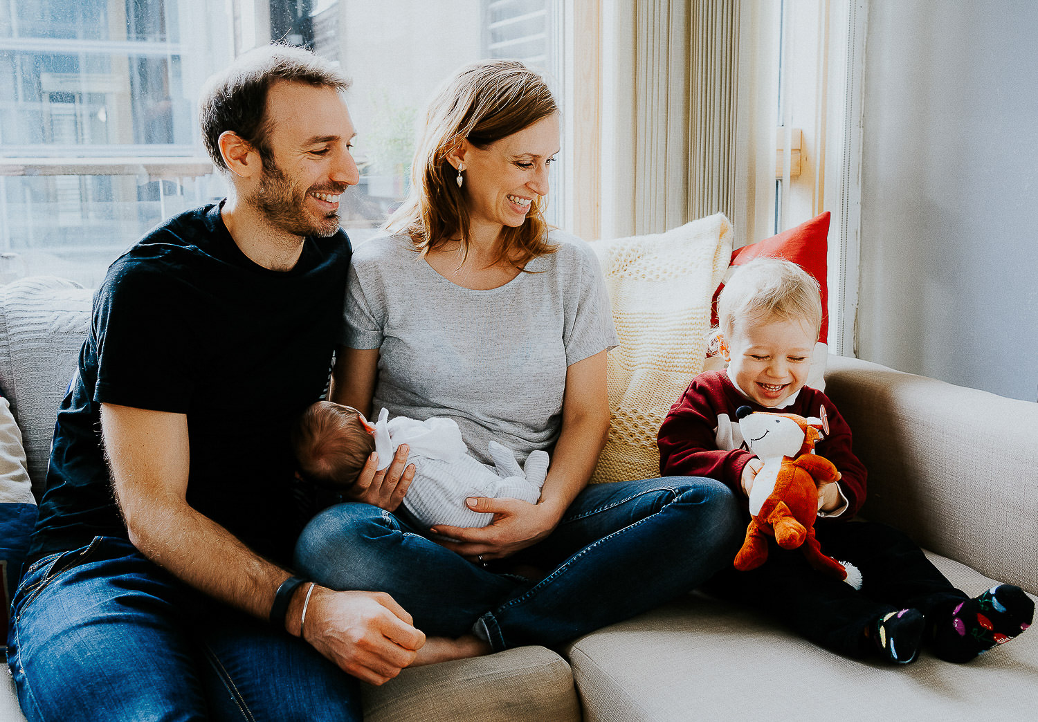 newborn baby and parents snuggling on sofa together