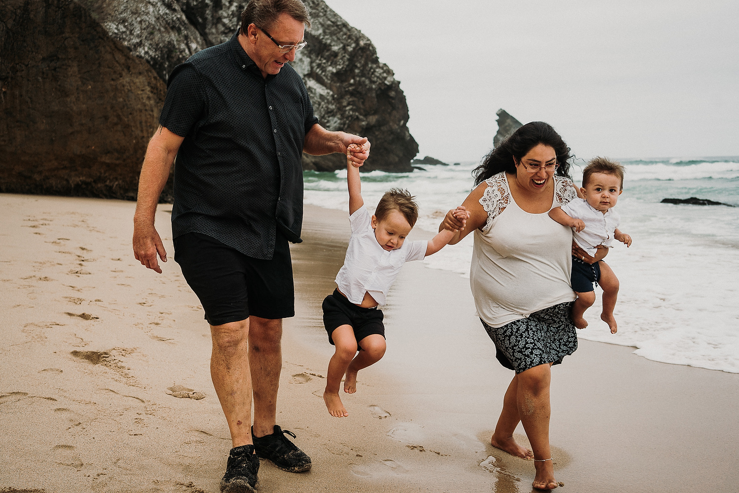family walking and laughing on beach in sintra, near lisbon in portugal